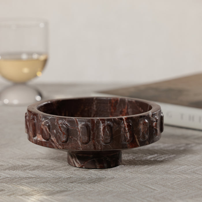 Marble-patterned bowl on a textured surface with a blurred glass and book in the background