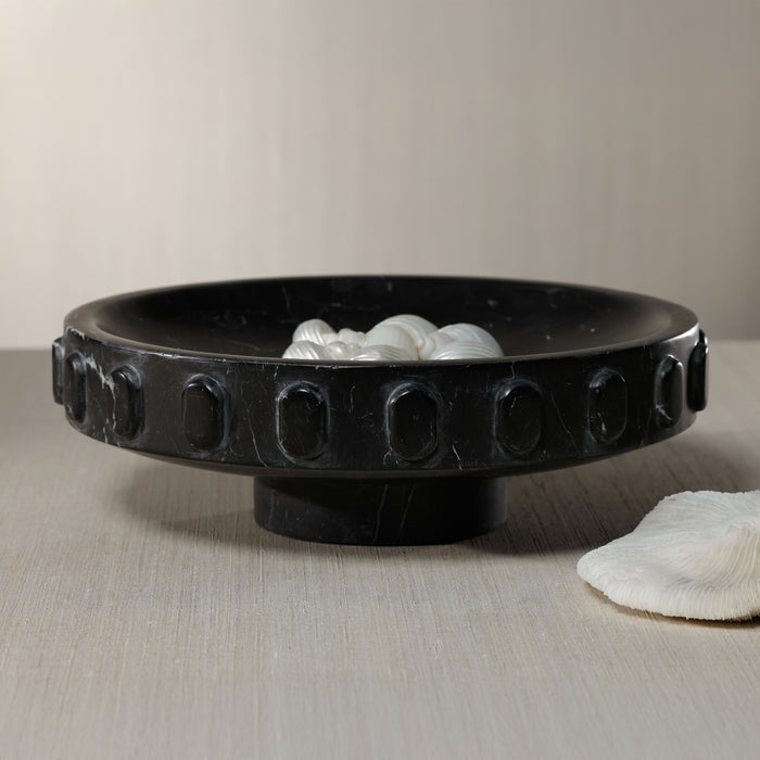 Black decorative bowl with shell-like objects on a neutral background