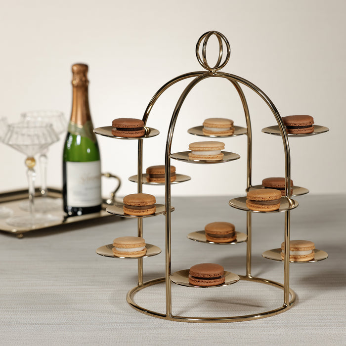 Gold tiered stand with macarons next to a bottle of champagne on a table.