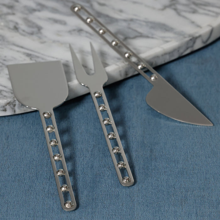 Set of three metal utensils on a blue surface with a marble background