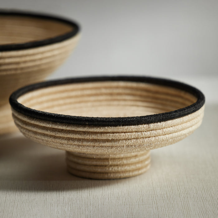 A coiled abaca footed small bowl with beige color and a black colored rim, displaying the traditional hand-woven technique.