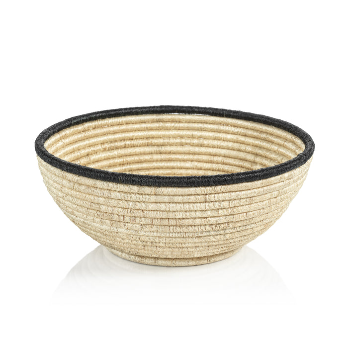 Large natural coiled Abaca bowl with black rim, woven straw texture on light beige background.