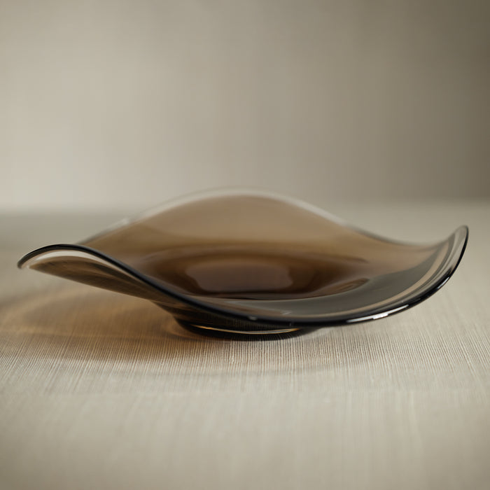 Brown glass plate on a textured surface with a neutral background