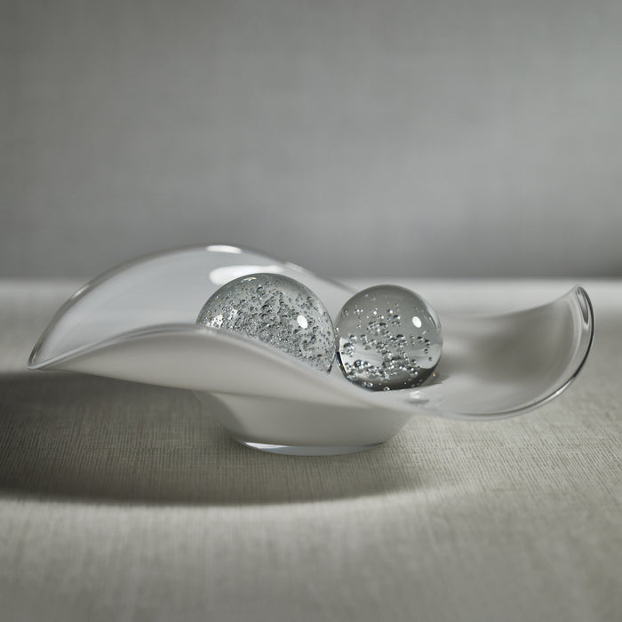 Glass bowl with two decorative glass spheres on a textured surface
