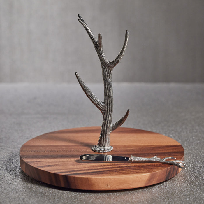 A wooden cheese and charcuterie board with a pewter antler stem used to hold charcuterie items like a knife.
