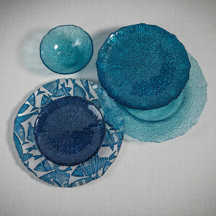 Set of blue ceramic plates and bowls on a textured gray surface