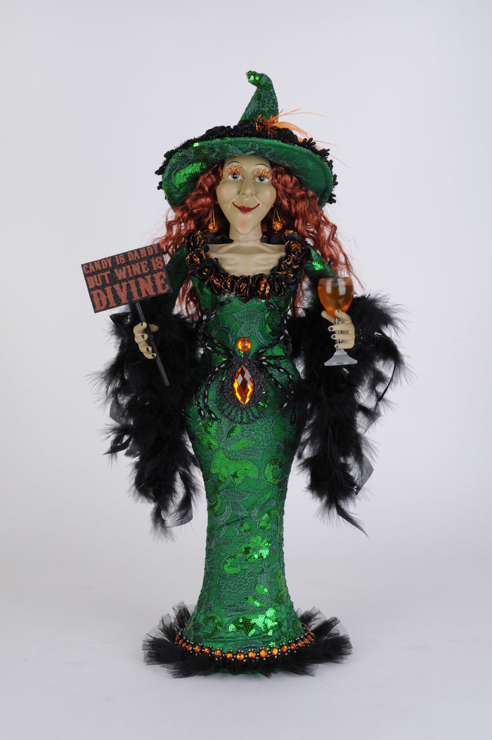 Decorative witch figurine with green dress, red hair, and a broom on a white background