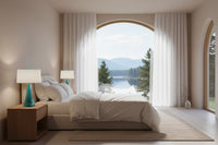 Aqua blue Murano glass lamps on nightstand tables with a white and beige platform bed, a textured natural rug, and an arched window with translucent white curtains, with a view of the Blue Ridge Mountains.