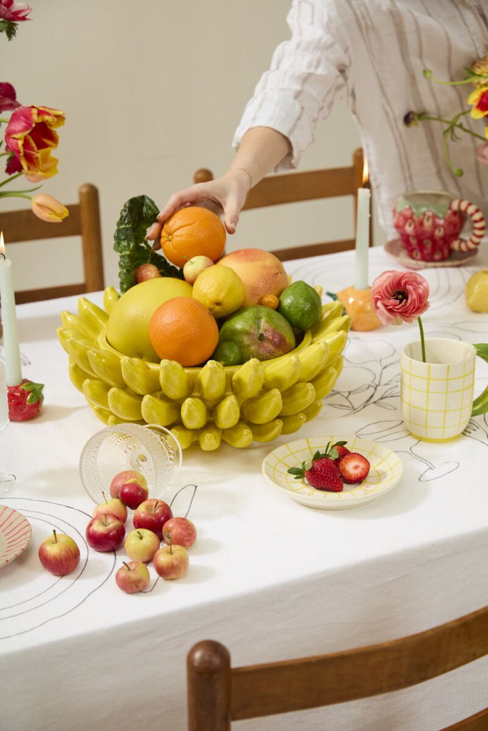 Table with fruits, glasses, and a person in the background