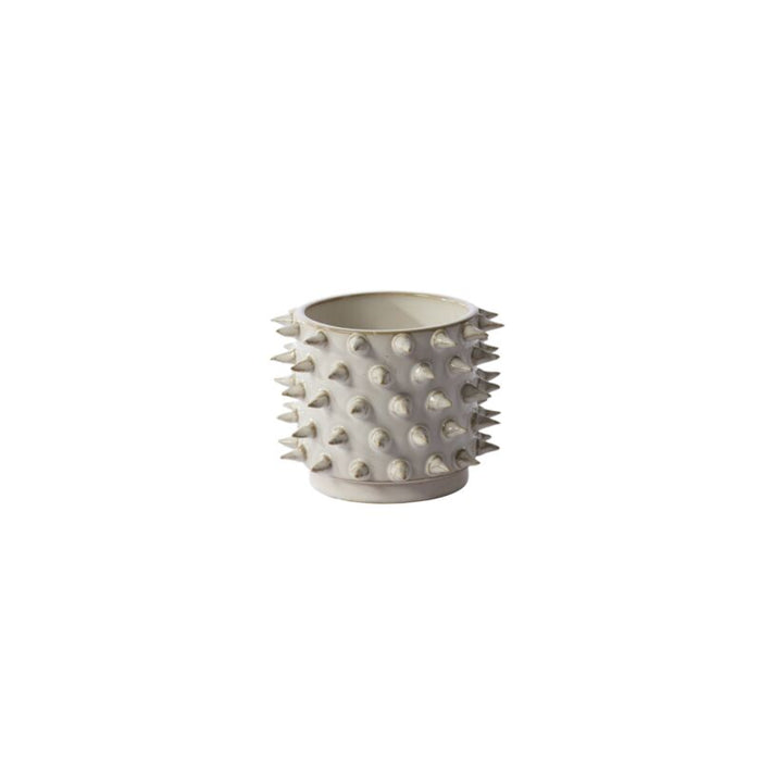 White pot with spiky design on a white background