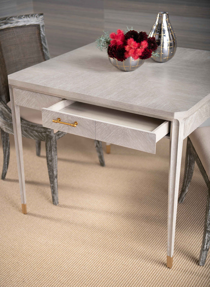 Gray dining table with a drawer, flowers, and decorative items in a room.