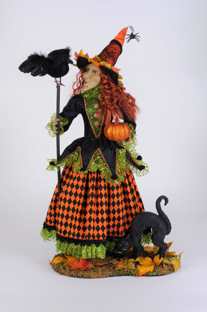Halloween-themed witch figurine with a broom, pumpkin, and black cat on a white background