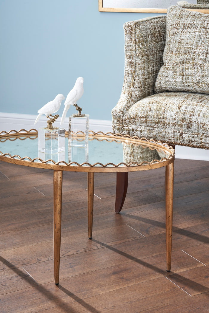Round glass coffee table with gold metal legs in a living room setting.