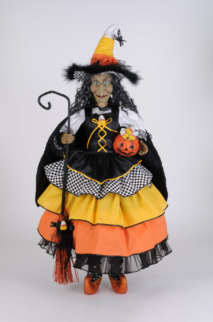 Halloween-themed doll in a witch costume with a broom and pumpkin on a white background