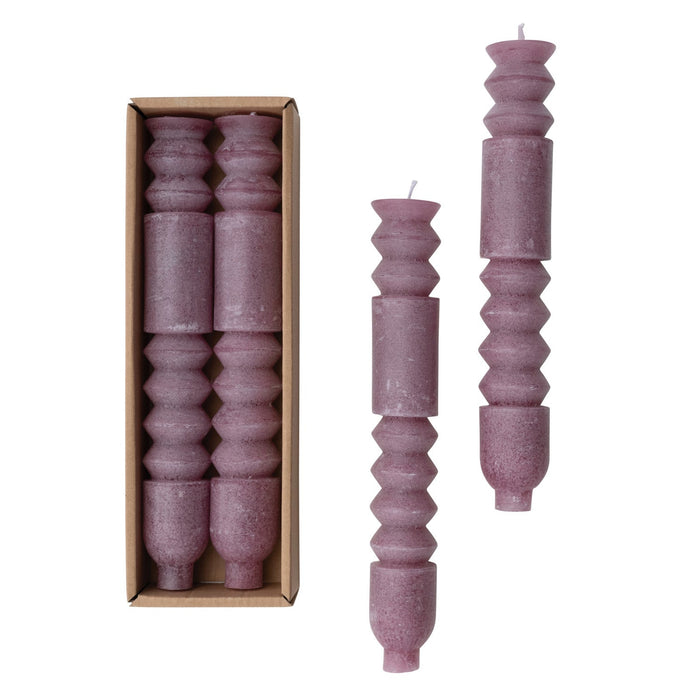 A set of two unscented purple totem taper candles presented in a cardboard box, with one candle outside showing the textured design.
