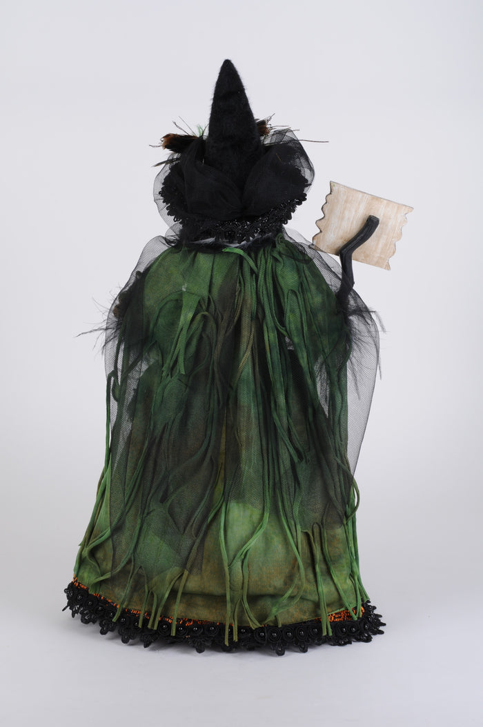 Witch figurine with green dress and black hat on a white background