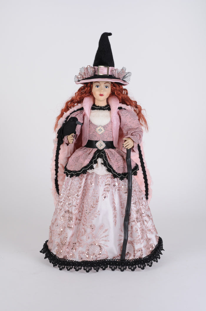 Decorative doll in a pink gown with black accents and a black hat on a white background