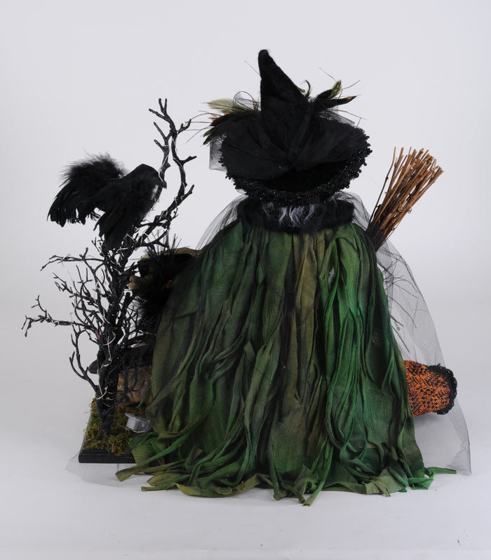 Halloween-themed decoration with a witch figure, broom, and crows on a white background