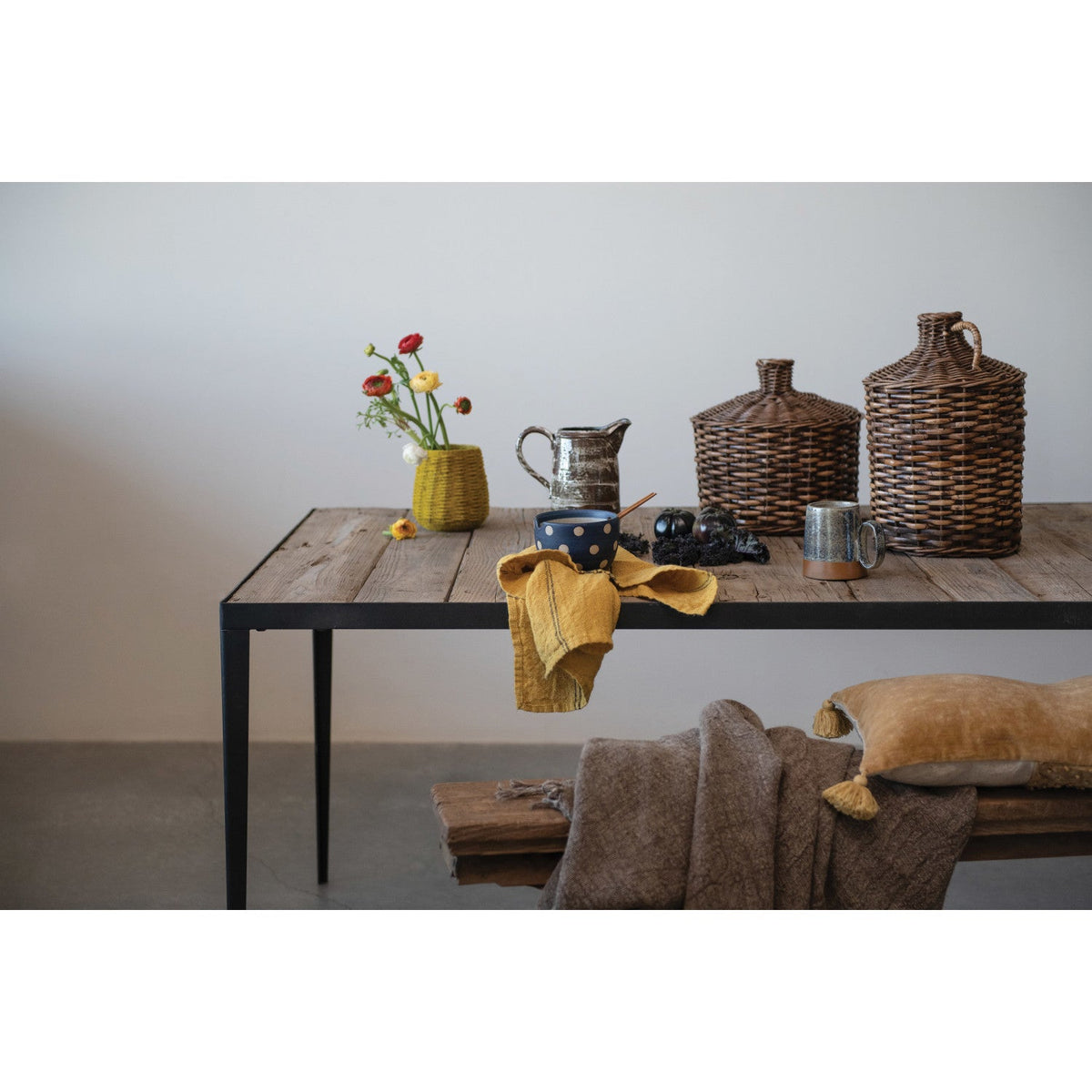 Wooden table with decorative items including vases and mugs against a plain wall.