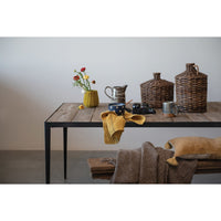 Wooden table with decorative items including vases and mugs against a plain wall.
