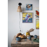 Table with bread and mugs, wall sconce, and framed rooster artwork on a light gray wall.