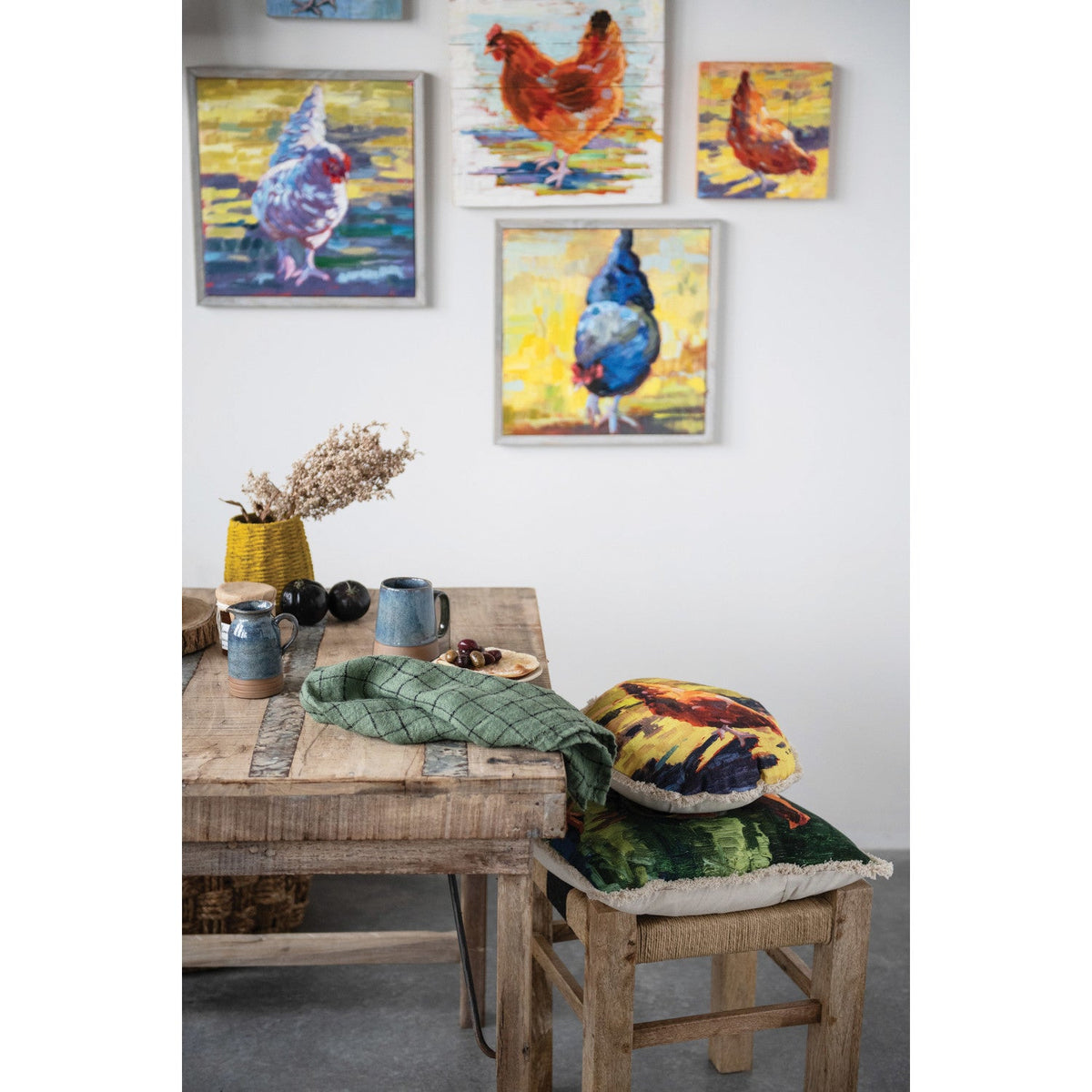 Dining room with a wooden table and chairs, featuring colorful chicken paintings on the wall.