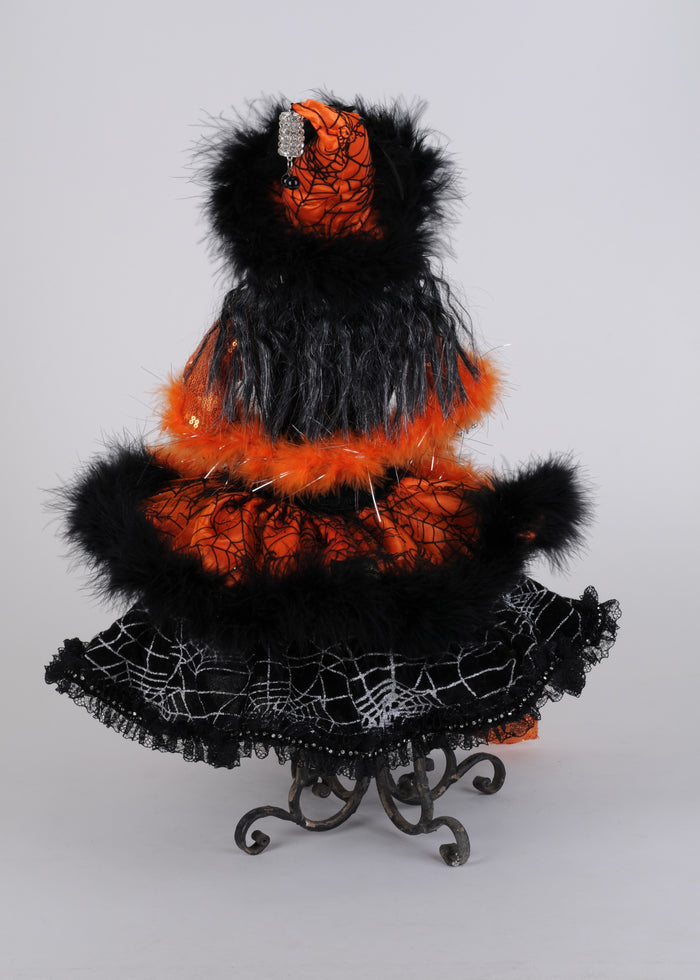 Halloween-themed decorative figure with black and orange feathers on a stand against a gray background
