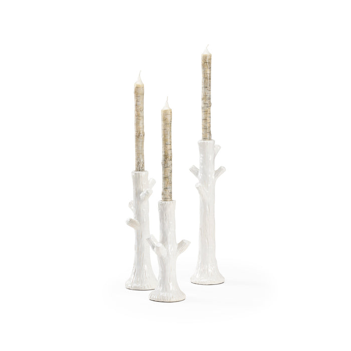 Set of three white candle holders with candles on a white background