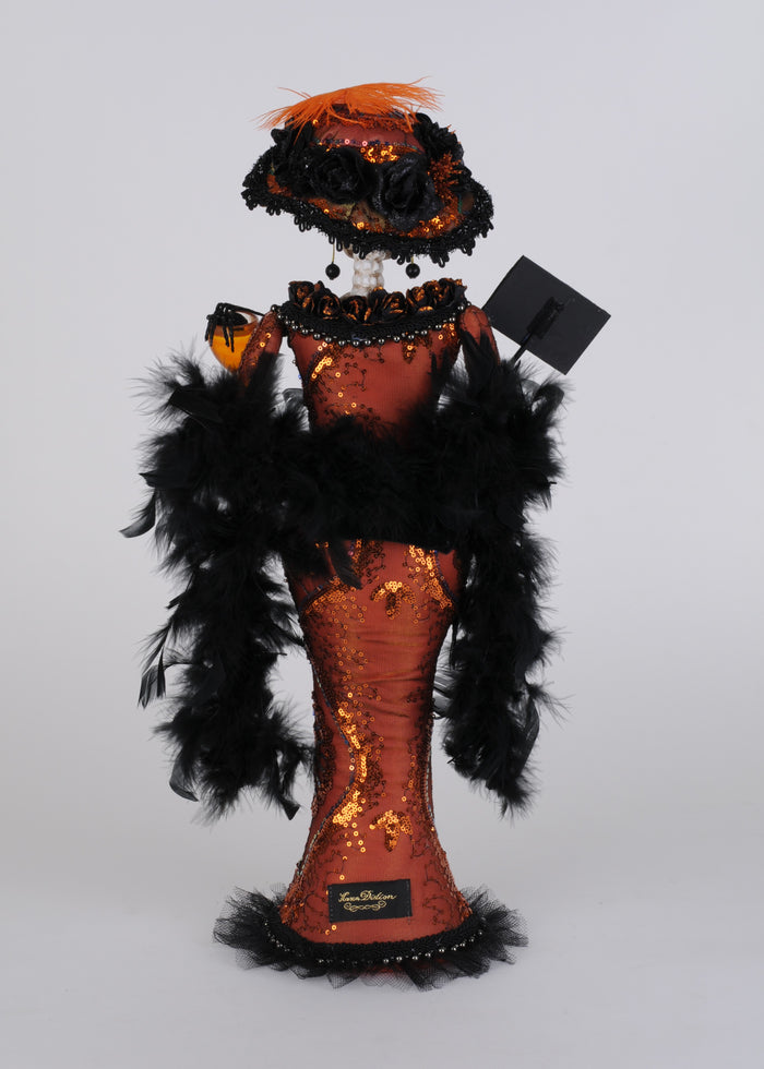 Decorative figure with orange sequin dress, black feathers, and a hat on a white background