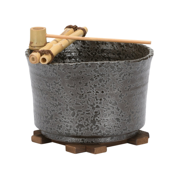 Ceramic pot with textured surface on a wooden stand, accompanied by bamboo sticks and chopsticks.