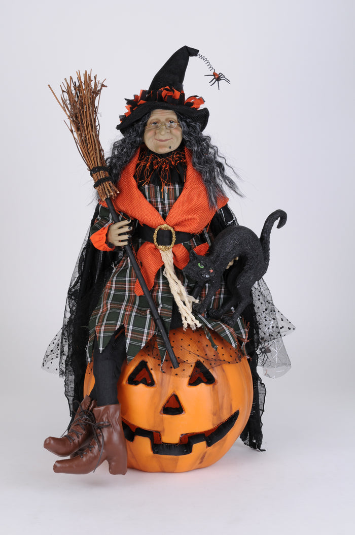 Halloween-themed doll with witch costume, broom, and pumpkin on a white background