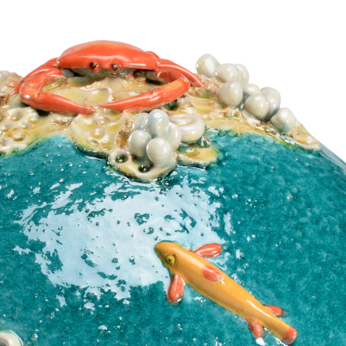 Decorative scene with a crab, fish, and pebbles on a blue surface