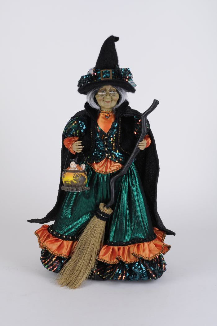 Decorative Halloween witch figurine with green dress and broom on a white background