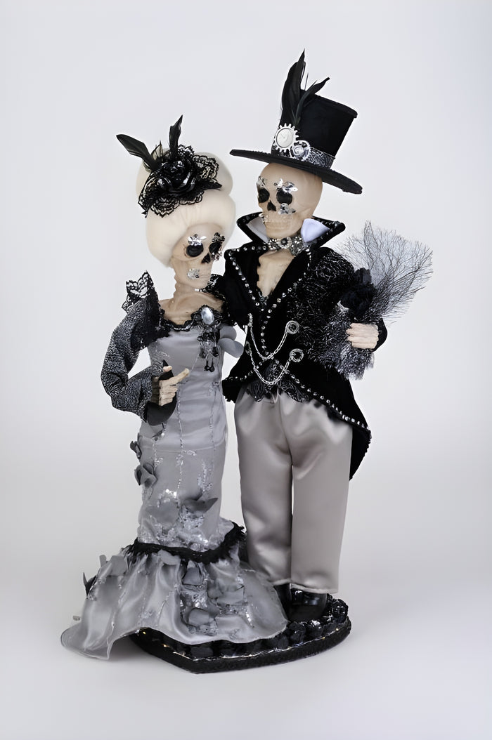 Decorative skeleton couple figurine in formal attire on a white background