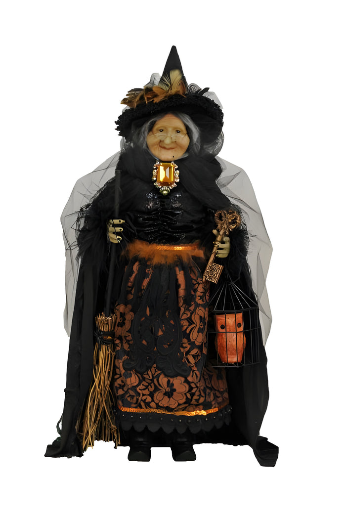 Decorative witch figure with black dress, hat, and lantern on a white background