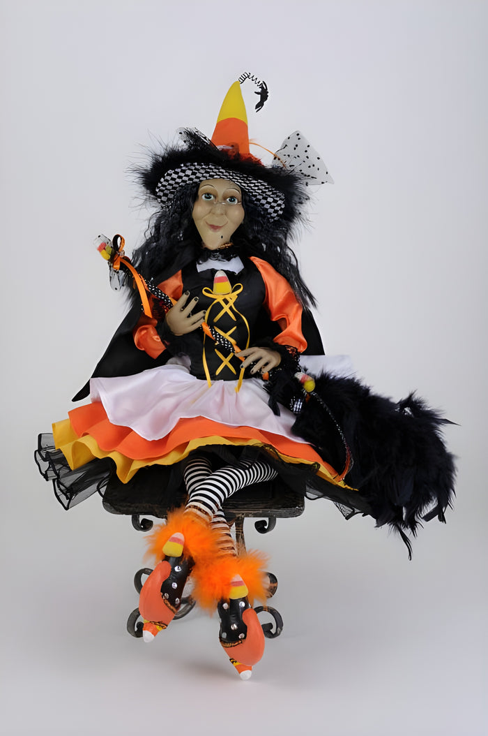 Halloween-themed doll with black hair, candy corn hat, and colorful outfit on a white background