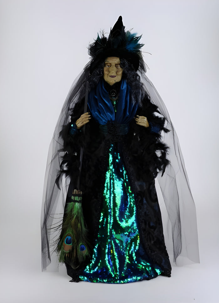 Vividly dressed figure with a black hat, blue scarf, and glowing green dress on a white background
