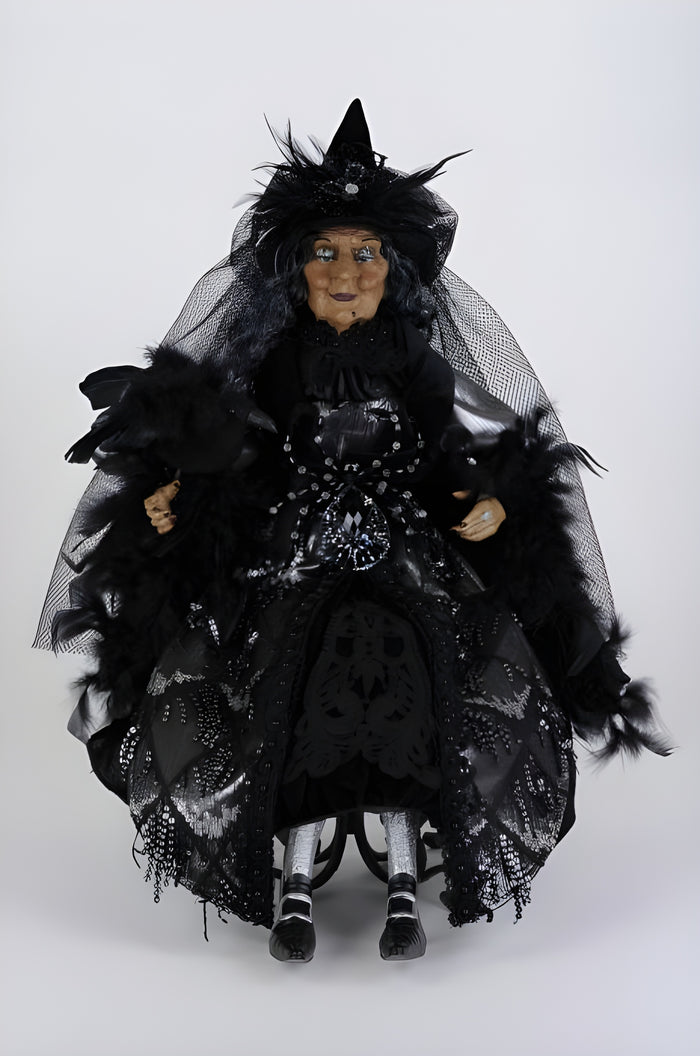 Black witch doll with a long black dress and hat on a white background