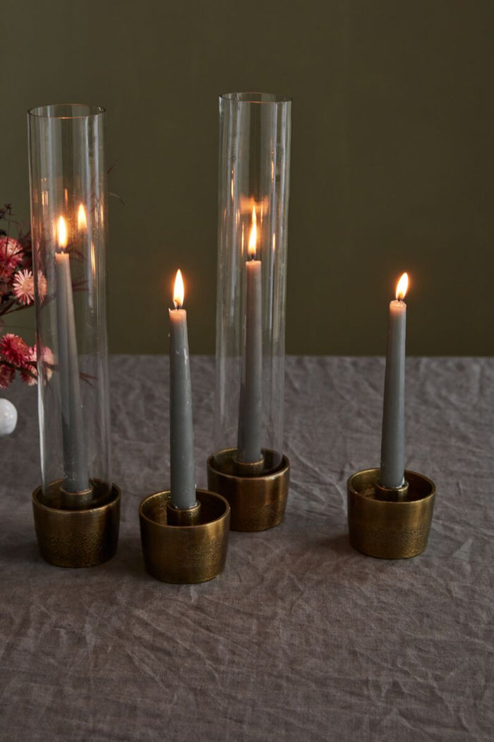 Four lit candles in brass holders on a textured surface with a dark background