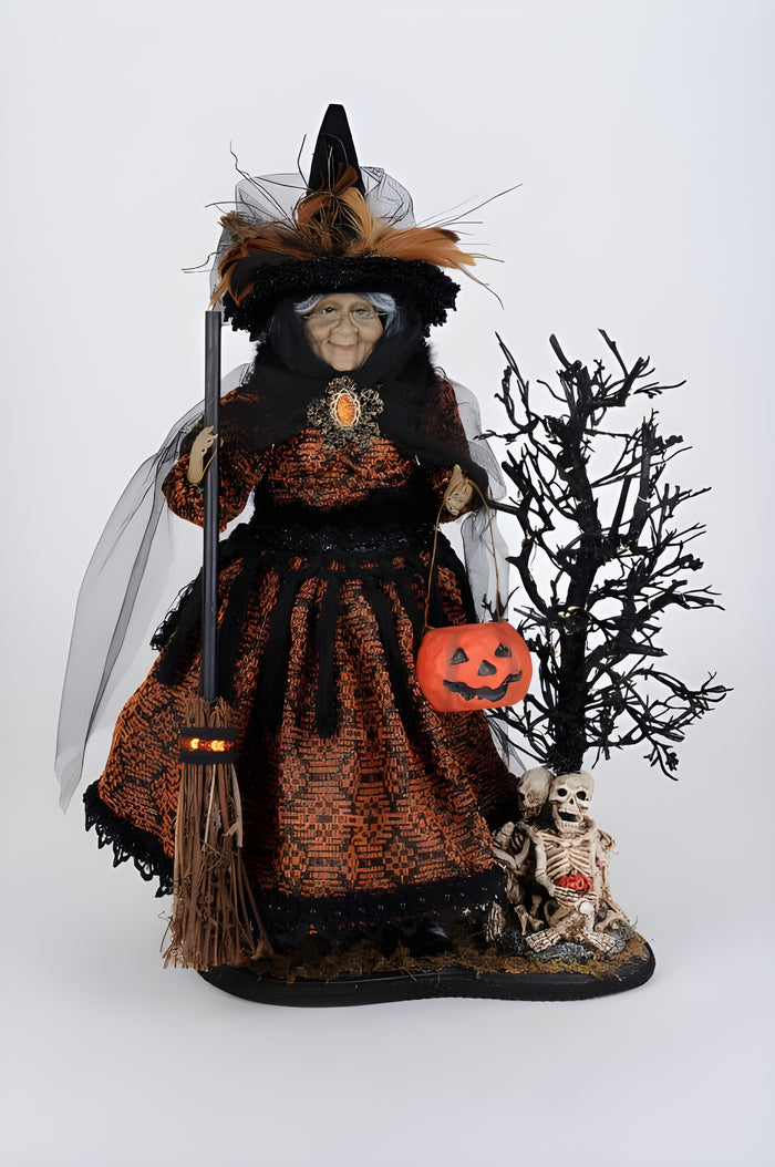 Halloween-themed doll in a black and orange outfit with a broom, pumpkin, and skeleton.
