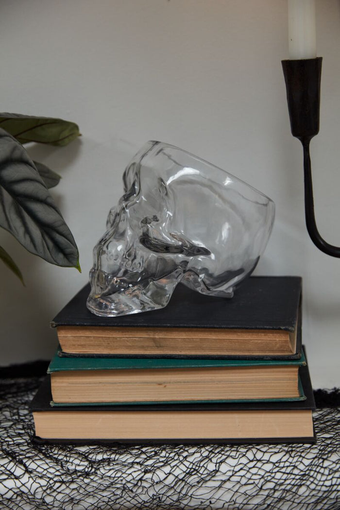 Clear glass rabbit sculpture on a stack of books with a candle in the background