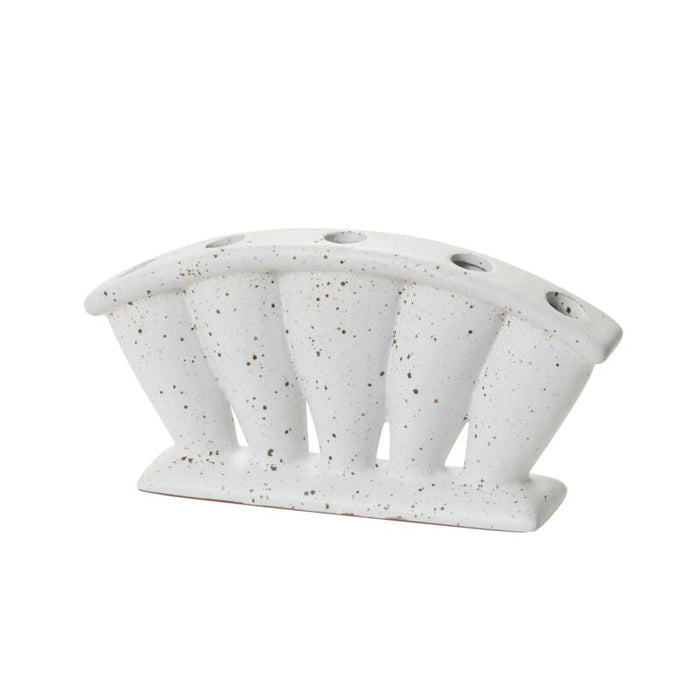 White speckled bud vase with diagonal arched slits, ceramic, on a flat base, plain background.