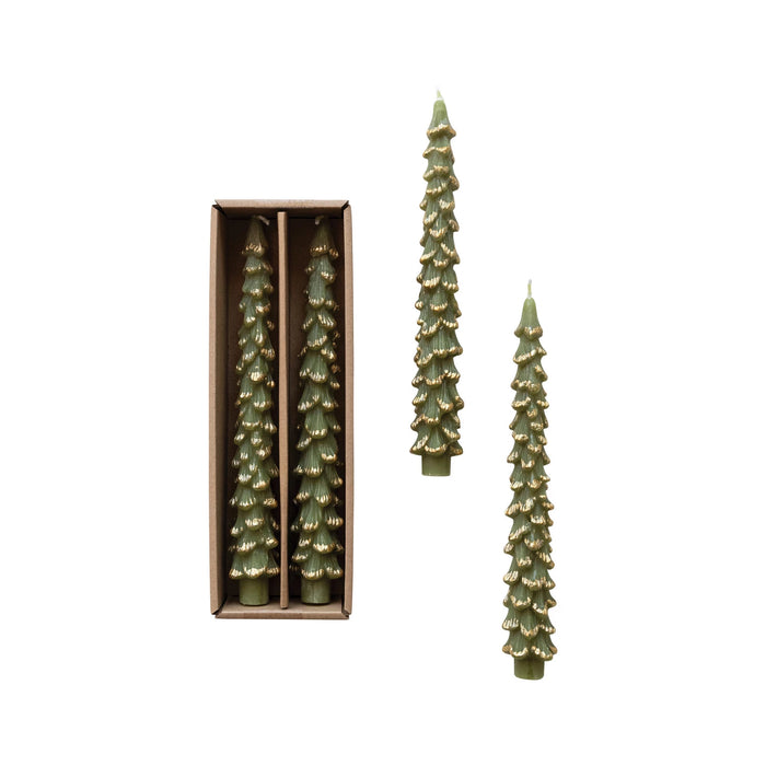 Two green tree-shaped taper candles with gold tips in a brown box, boxed pair with pine-branch texture on a white background
