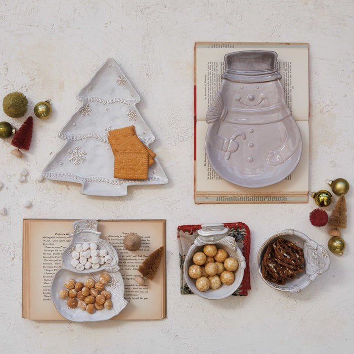 Stoneware Santa and snowman shaped bowls, light gray ceramic; stacked tree shapes and cookies around on book pages and