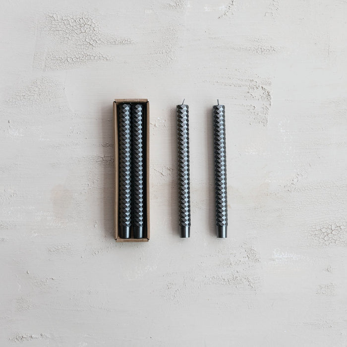 Set of two unscented faceted dark gray taper candles; one pair in a cardboard box, others displayed upright on a light