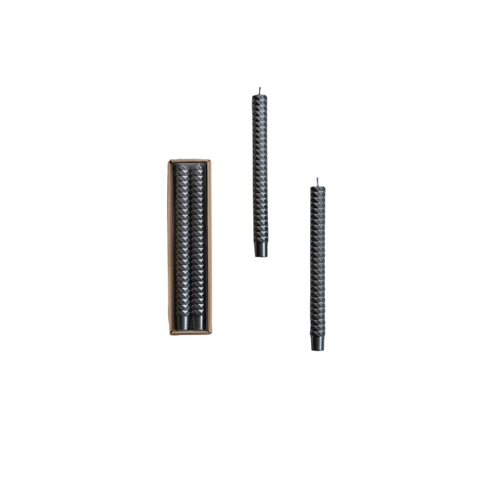 A set of two unscented faceted taper candles displayed alongside their packaging box.
