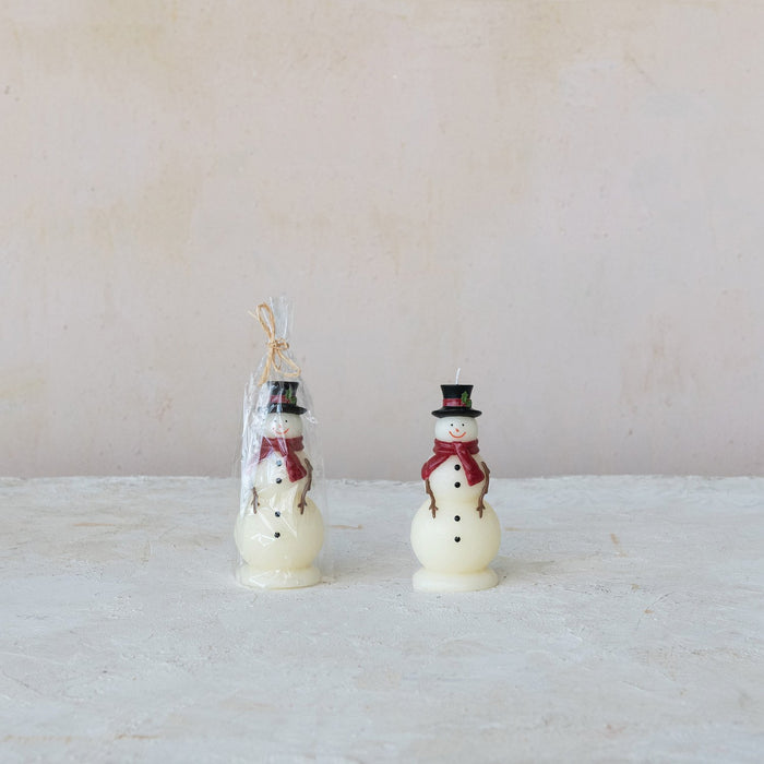 Two white snowman candles with black top hats, red scarves, and coal-like buttons; one wrapped in clear plastic with twine